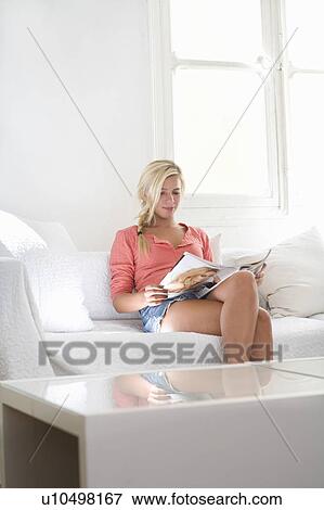 Young woman reads magazine on couch View Large Photo Image Stock Photo - Young woman reads magazine on couch. Fotosearch
