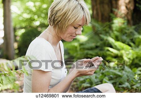 Stock Image - Young woman sitting in garden. Fotosearch