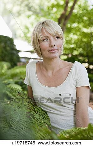 Stock Photograph - Young woman sitting in garden. Fotosearch