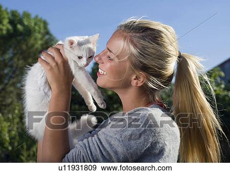 Young woman smiles holding kitten View Large Photo Image Stock Photo - Young woman smiles holding kitten. Fotosearch