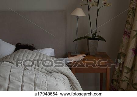 Picture - Young woman switching off phone alarm. Fotosearch