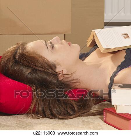 Stock Image - Young woman with books and boxes. Fotosearch