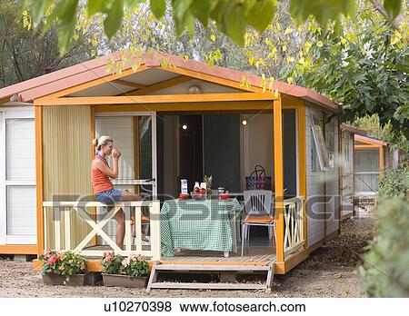 Stock Photo - Young woman with drink sits on terrace. Fotosearch