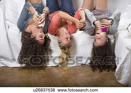 Young women lay on couch with cell phone View Large Photo Image Stock Photo - Young women lay on couch with cell phone. Fotosearch