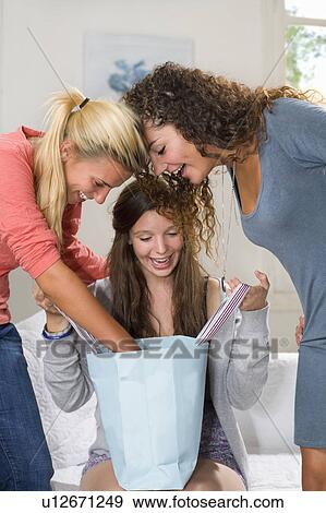 Young women look in shopping bag at home View Large Photo Image Stock Photo - Young women look in shopping bag at home. Fotosearch