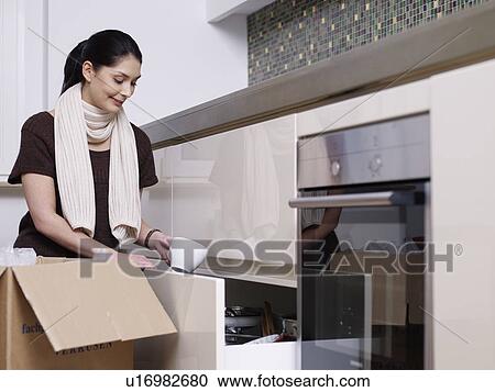 Stock Image - Young women unpacking boxes. Fotosearch