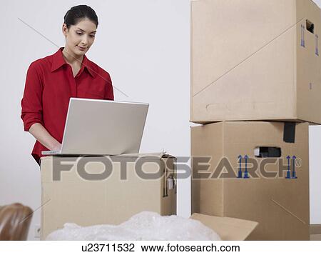 Young women with laptop and boxes View Large Photo Image Stock Image - Young women with laptop and boxes. Fotosearch