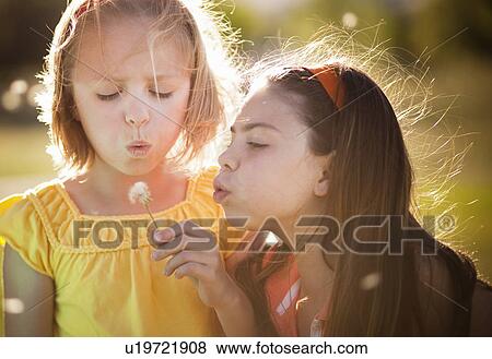 2 girls blowing on dandelion View Large Photo Image Stock Photo - 2 girls blowing on dandelion. Fotosearch