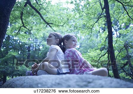 2 girls sitting on a big roc in forest View Large Photo Image Stock Photograph - 2 girls sitting on a big roc in forest. Fotosearch