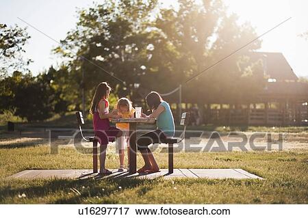 Stock Photo - 3 girls sitting in park painting. Fotosearch