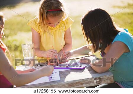 3 young girls sitting at table painting View Large Photo Image Stock Photography - 3 young girls sitting at table painting. Fotosearch