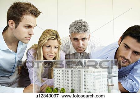Stock Photo - 4 people looking at architectural design. Fotosearch