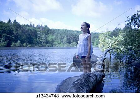 Stock Photo - 7y girl standing by a lake. Fotosearch