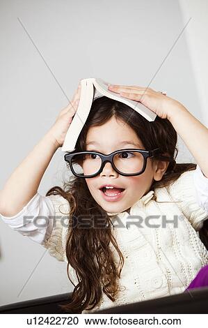 Stock Image - Astonished girl with book on her head. Fotosearch