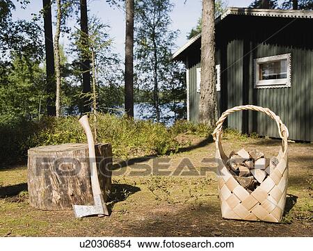 Picture - Axe and firewood by wooden cabin. Fotosearch