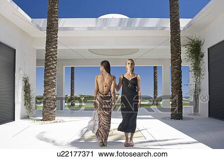 Stock Image - Beautiful women standing in modern villa. Fotosearch