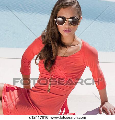 Beautiful young woman sitting by pool View Large Photo Image Stock Photograph - Beautiful young woman sitting by pool. Fotosearch