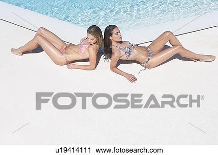 Beautiful young women relaxing by pool View Large Photo Image Stock Image - Beautiful young women relaxing by pool. Fotosearch