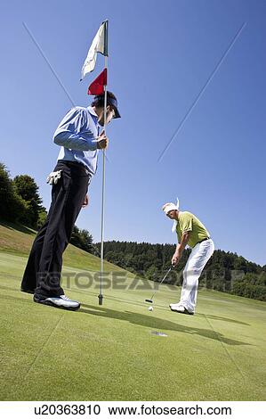 Stock Image - Blindfolded golfing man and Caddy. Fotosearch