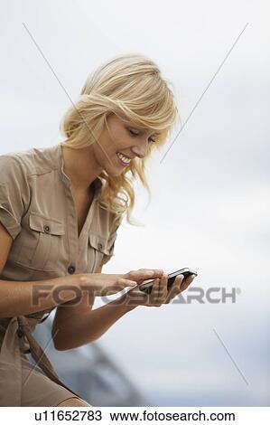 Blonde woman typing in mobile phone View Large Photo Image Stock Image - Blonde woman typing in mobile phone. Fotosearch