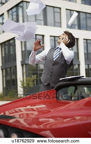 Stock Photo - Blown away papers from mans electric car. Fotosearch