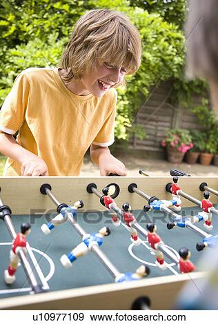 Boy (10-12) playing table football View Large Photo Image Stock Photo - Boy (10-12) playing table football. Fotosearch