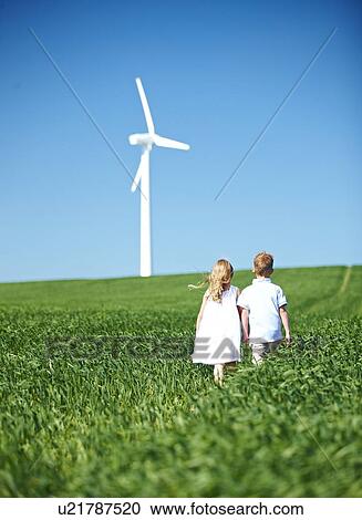 Stock Image - Boy and girl lookng at wind turbine. Fotosearch