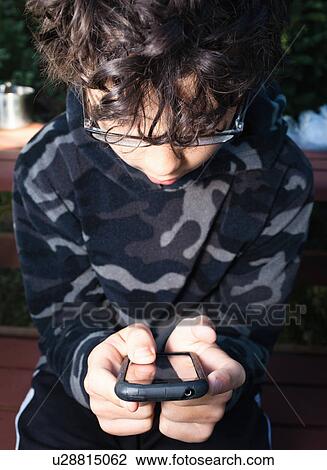Stock Image - Boy concentrating on phone. Fotosearch