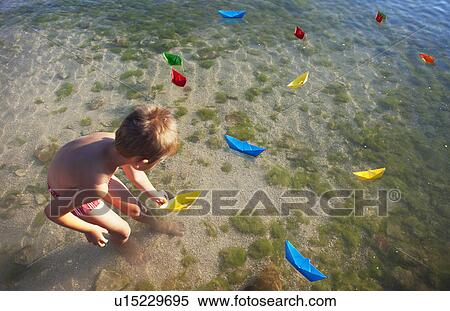 Boy floating paper boats at the beach View Large Photo Image Stock Photography - Boy floating paper boats at the beach. Fotosearch