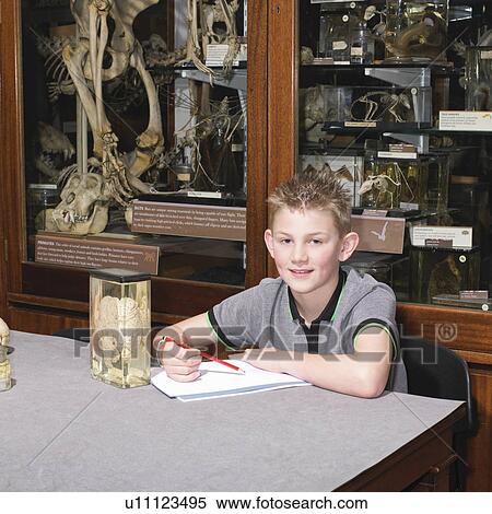 Stock Photography - Boy in sitting at table in museum. Fotosearch
