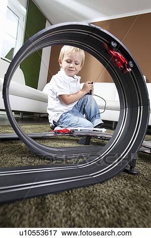 Stock Photo - Boy playing with slot car racing track. Fotosearch