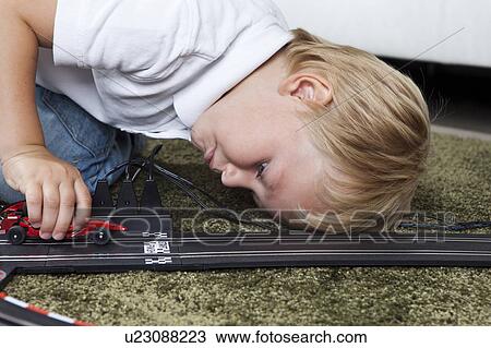 Stock Image - Boy playing with slot race track. Fotosearch