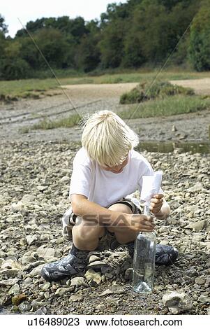 Boy pulling message from bottle View Large Photo Image Stock Image - Boy pulling message from bottle. Fotosearch