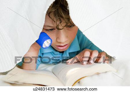 Stock Image - Boy reading with flashlight. Fotosearch