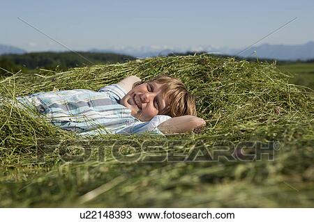 Stock Image - Boy resting in grass, happy. Fotosearch