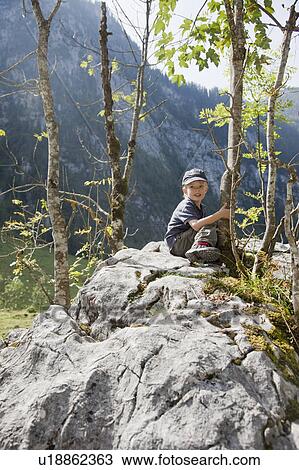 Boy sitting on a stone View Large Photo Image Stock Image - Boy sitting on a stone. Fotosearch