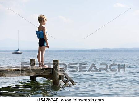 Boy standing on pier with swimming belt View Large Photo Image Stock Image - Boy standing on pier with swimming belt. Fotosearch