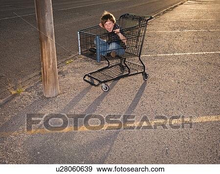 Stock Photo - Boy using shopping cart as a vehicle. Fotosearch