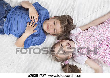 Brother and sister lying on rug View Large Photo Image Stock Photo - Brother and sister lying on rug. Fotosearch