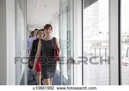 Stock Image - Business people walking down corridor. Fotosearch