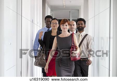Stock Image - Business people walking down corridor. Fotosearch