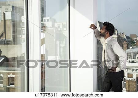 Businessman looking out of office window View Large Photo Image Stock Image - Businessman looking out of office window. Fotosearch