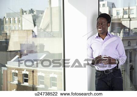 Stock Image - Businessman looking out of office window. Fotosearch