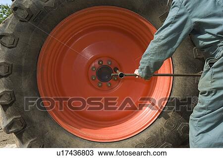 Stock Image - Changing tractor wheel. Fotosearch