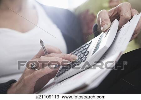 Stock Photo - Close-up of woman's hands on calculator. Fotosearch