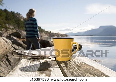Stock Image - Coffee and paper, woman in background. Fotosearch
