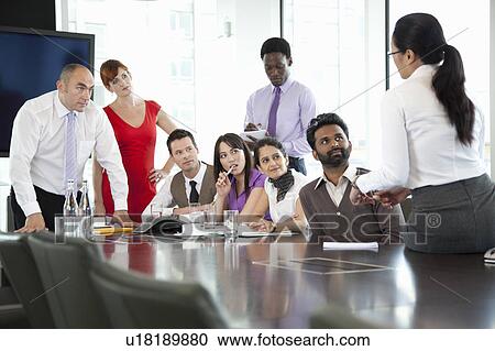 Stock Image - Colleagues listening to businesswoman. Fotosearch