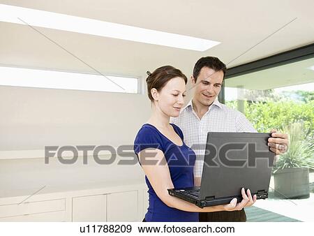 Colleagues look at lap top in office View Large Photo Image Stock Photo - Colleagues look at lap top in office. Fotosearch
