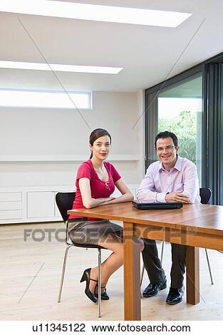 Stock Image - Confident man & woman in modern office. Fotosearch