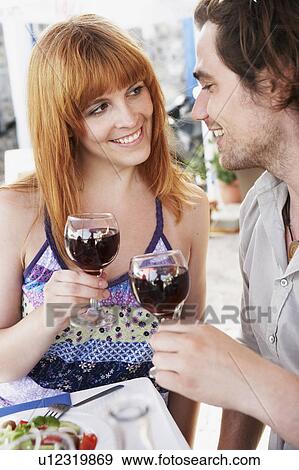 Stock Photo - Couple chinking glasses with red wine. Fotosearch